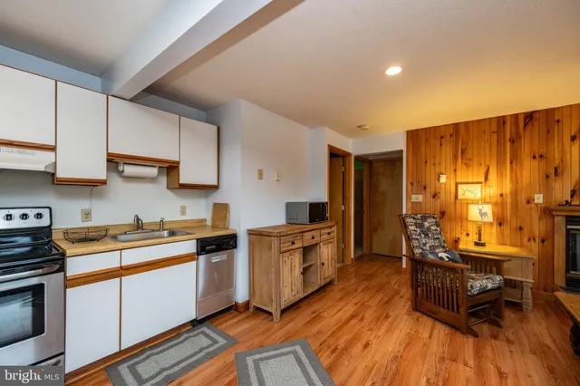 a kitchen with stainless steel appliances a stove a sink cabinets and wooden floor