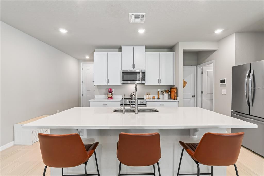 32502 Limitless Place Wesley Chapel, FL 33545 - Photo 13 of 67 a kitchen with stainless steel appliances a white table chairs and a refrigerator