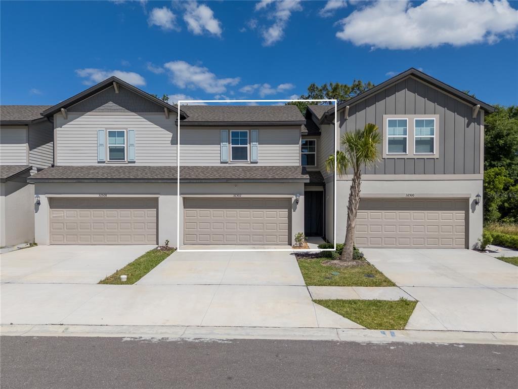 32502 Limitless Place Wesley Chapel, FL 33545 - Photo 3 of 67 a view of a white house with a yard and large parking space