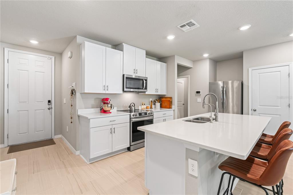 32502 Limitless Place Wesley Chapel, FL 33545 - Photo 10 of 67 a kitchen with white cabinets and stainless steel appliances