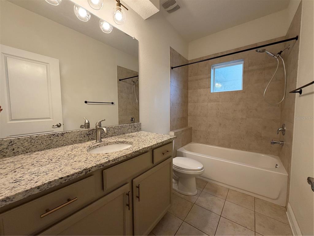 1736 West Walnut Street Tampa, FL 33607 - Photo 11 of 22 a bathroom with a granite countertop sink a toilet a mirror a bathtub and shower