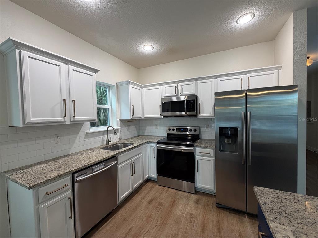 1736 West Walnut Street Tampa, FL 33607 - Photo 4 of 22 a kitchen with stainless steel appliances granite countertop a refrigerator a stove top oven a sink and dishwasher