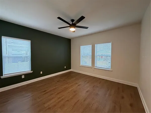 a view of an empty room with a window and wooden floor