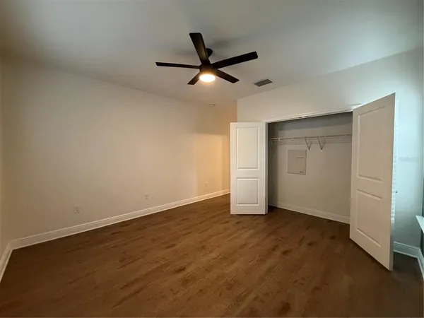 an empty room with closet and a ceiling fan