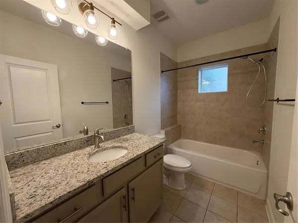 a bathroom with a granite countertop sink a toilet a mirror a bathtub and shower
