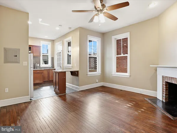 a view of a livingroom with wooden floor a ceiling fan and windows