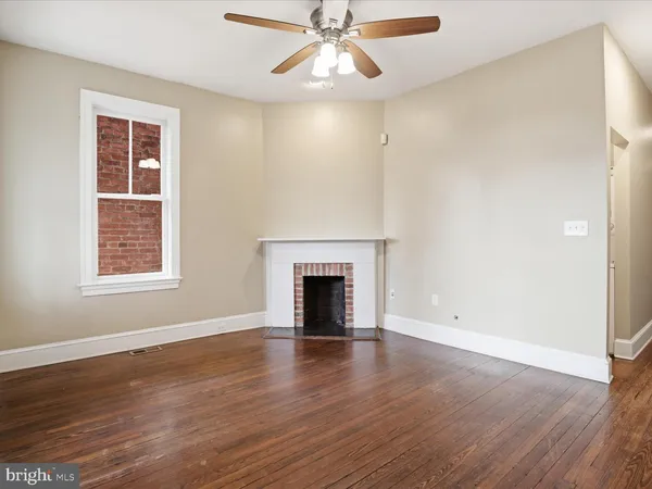 an empty room with wooden floor windows and fireplace