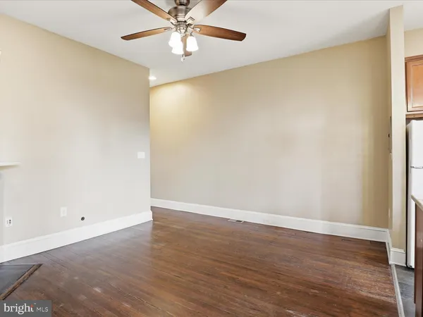 an empty room with wooden floor and fan