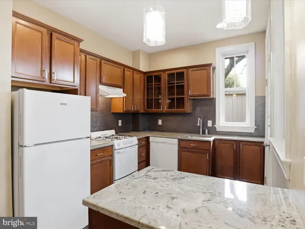 a kitchen with stainless steel appliances granite countertop a refrigerator a stove a sink dishwasher and white cabinets with wooden floor
