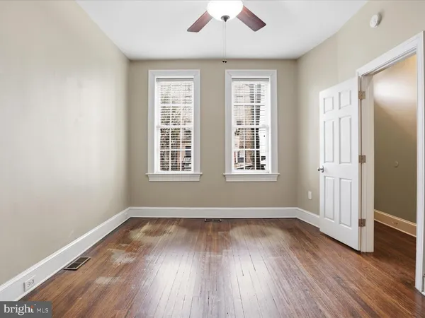 an empty room with wooden floor and windows