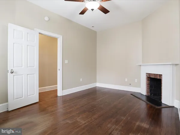 an empty room with wooden floor fireplace and windows