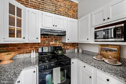 a kitchen with granite countertop a stove sink and cabinets