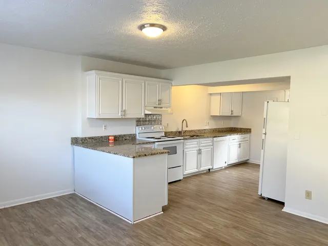 a kitchen with granite countertop white cabinets and white appliances