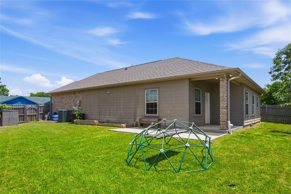 1502 Reed Street Greenville, TX 75401 - Photo 25 of 26 Expansive lawn featuring a covered patio, brick accent column, and partial wood privacy fencing