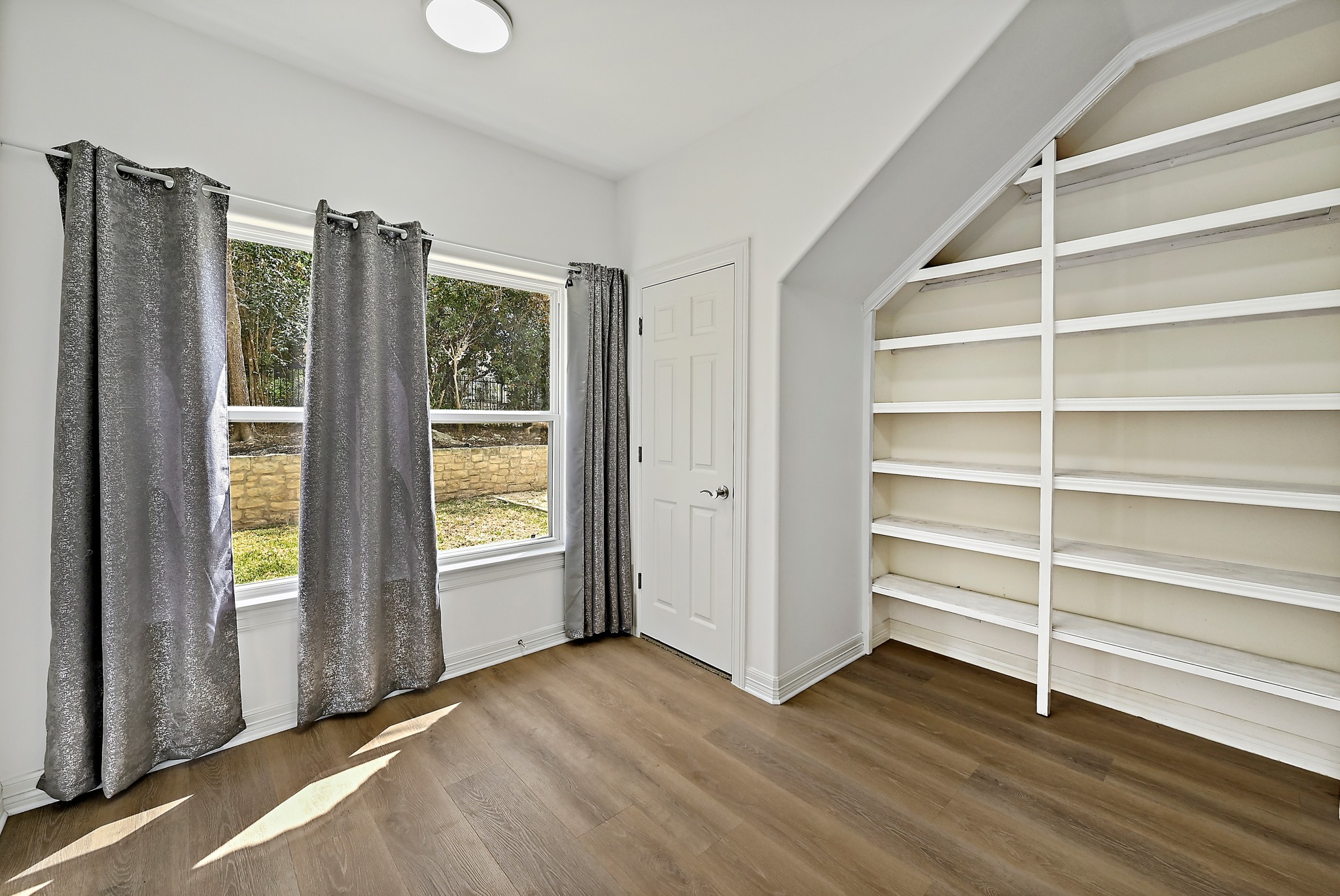 22 Hedgebrook Way The Hills, TX 78738 - Photo 20 of 40 a view of an empty room with a window and wooden floor