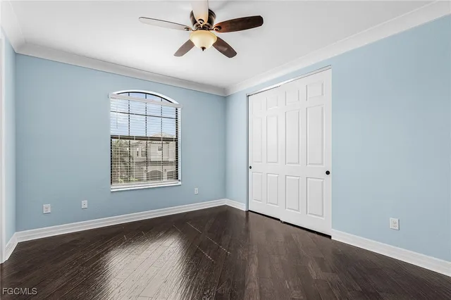 an empty room with wooden floor chandelier fan and windows
