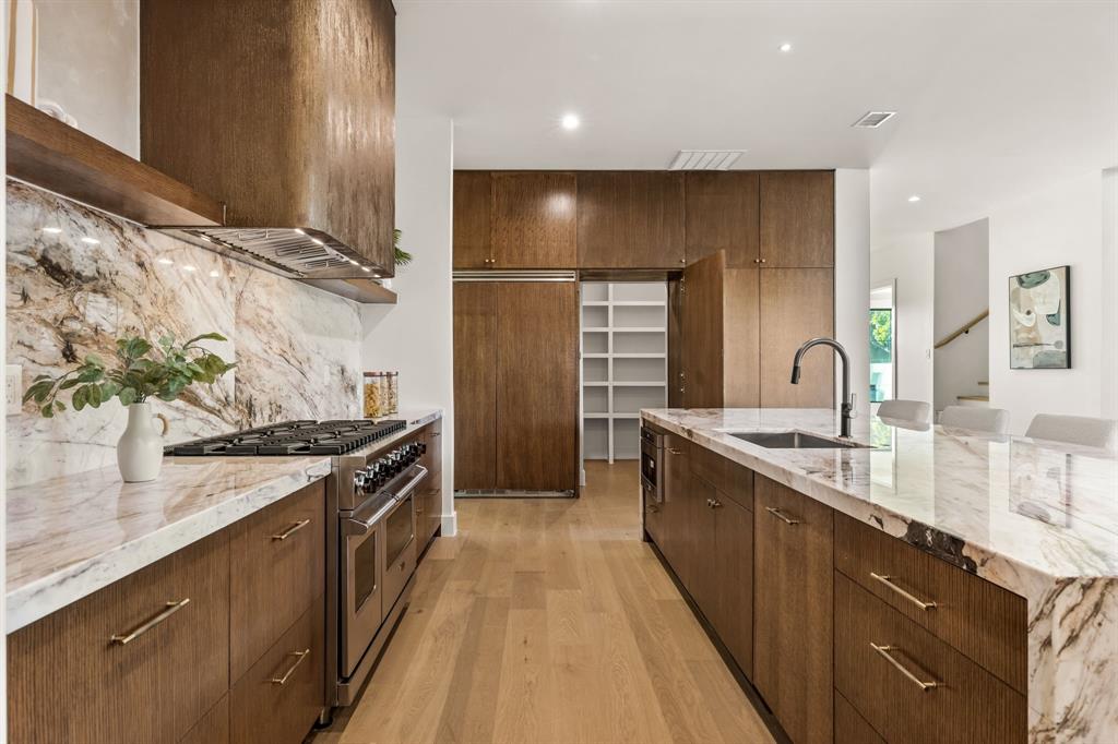 702 Mockingbird Lane Coppell, TX 75019 - Photo 13 of 32 Kitchen with light stone countertops, double oven range, light wood finished floors, backsplash, and recessed lighting
