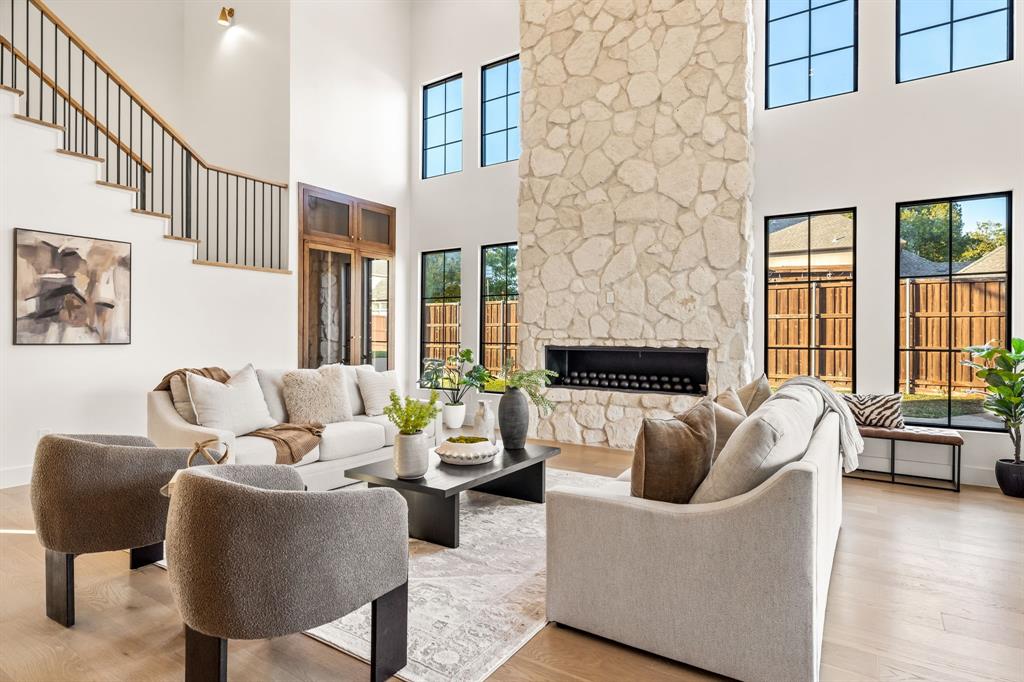 702 Mockingbird Lane Coppell, TX 75019 - Photo 10 of 32 Living room featuring wood finished floors, a stone fireplace, and a towering ceiling