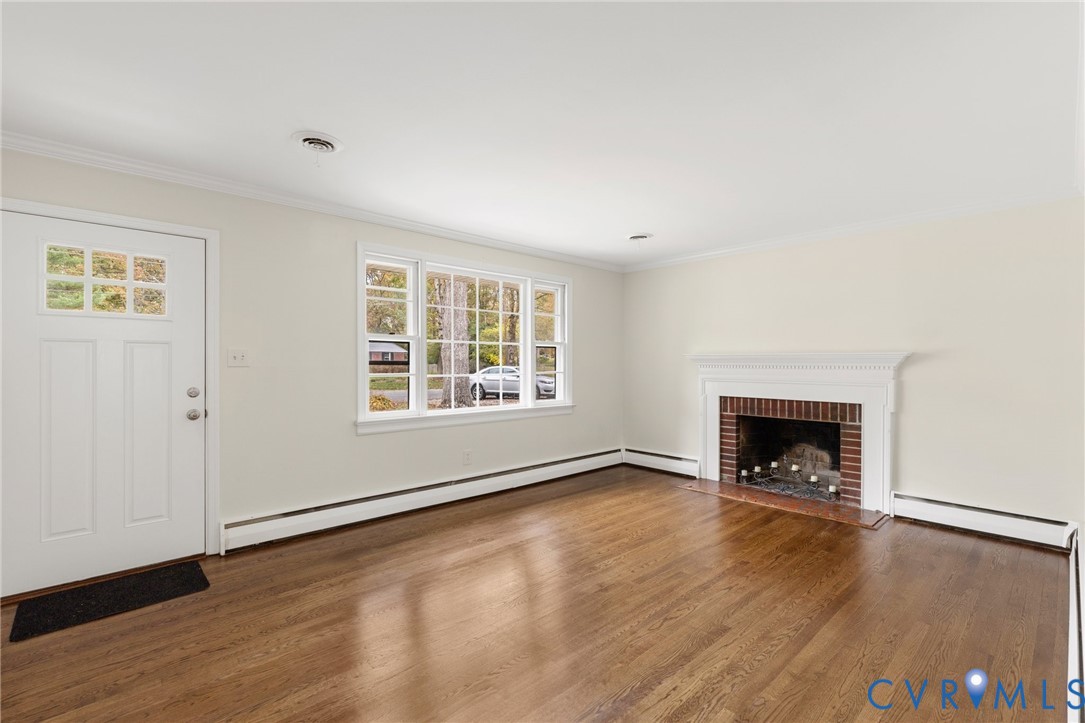 9303 Edson Road Henrico, VA 23229 - Photo 5 of 31 an empty room with wooden floor fireplace and windows