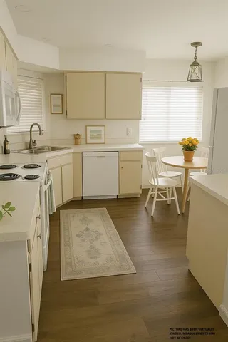 a kitchen with a sink stove and white cabinets with wooden floor