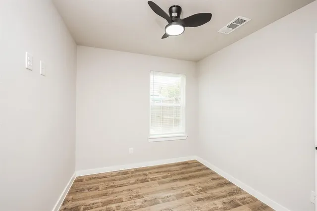 an empty room with a window and ceiling fan