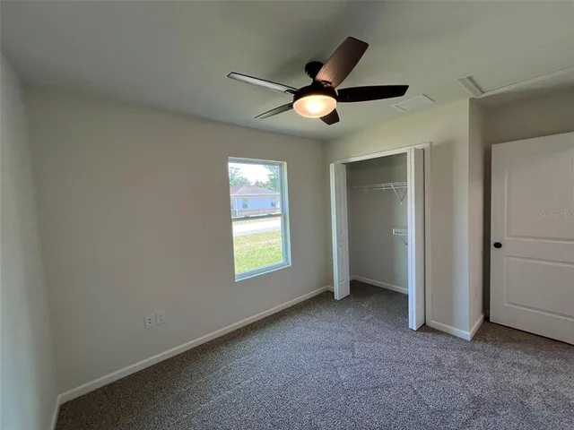 an empty room with window and a ceiling fan