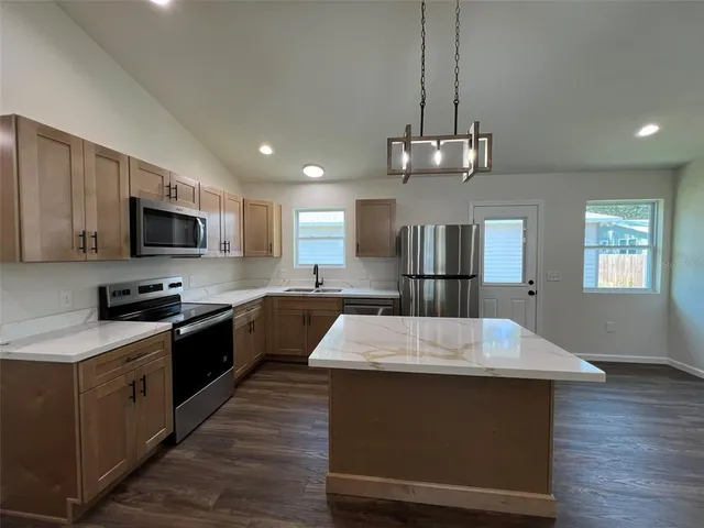 a large kitchen with stainless steel appliances granite countertop a oven a stove and a wooden floors