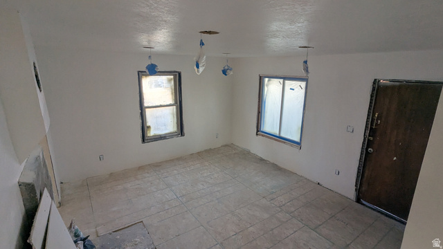 436 Rose Avenue Price, UT 84501 - Photo 8 of 36 Spacious room with white walls, two windows, and a dark entry door