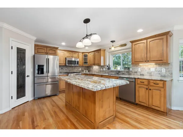 a kitchen with stainless steel appliances granite countertop a stove refrigerator and a sink