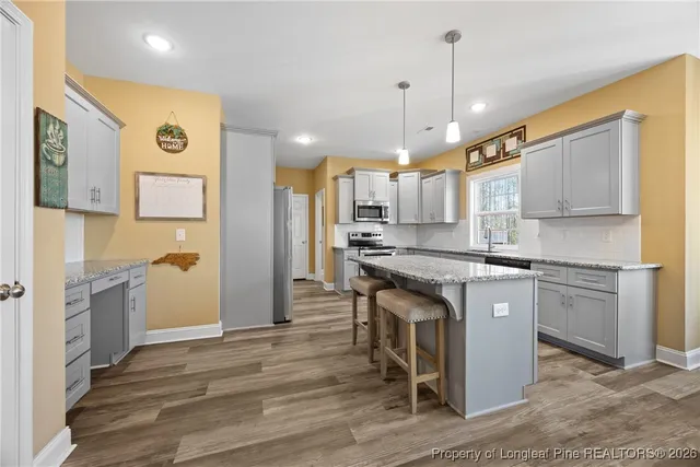 a kitchen with stainless steel appliances granite countertop a sink a stove a refrigerator and island with wooden floor