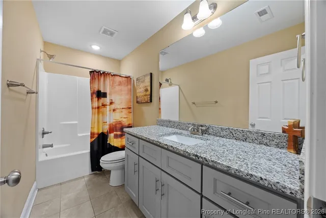 a bathroom with a granite countertop sink a mirror a toilet and shower