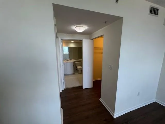a view of a hallway with wooden floor and a bathroom