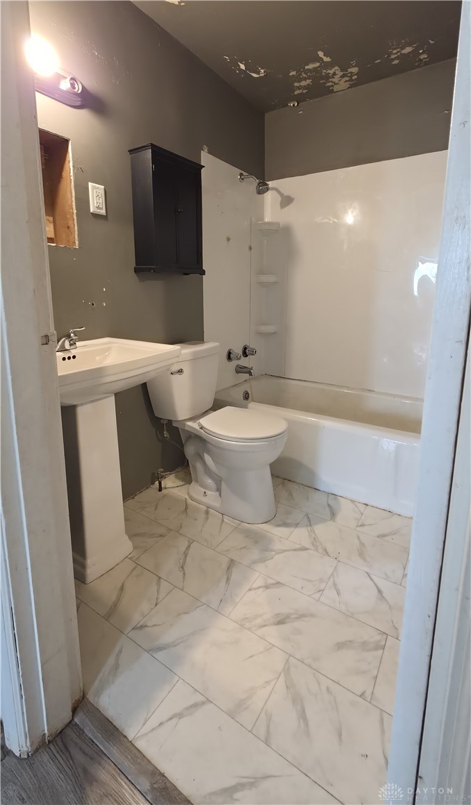3109 Shroyer Road Kettering, OH 45429 - Photo 2 of 25 This functional bathroom features a shower-tub combination and classic pedestal sink, offering practicality and charm.