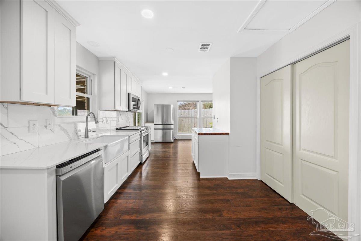 2521 Tomlinson Road Pensacola, FL 32526 - Photo 13 of 30 a kitchen with granite countertop a refrigerator a sink and white cabinets