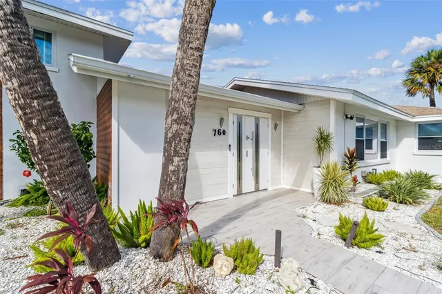 a kitchen with stainless steel appliances granite countertop a sink a stove a refrigerator and white cabinets with wooden floor