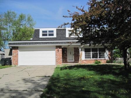 a front view of a house with a garden and trees