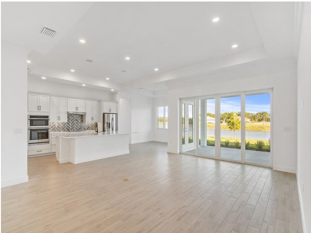 5865 Palmetto Preserve Road Vero Beach, FL 32967 - Photo 7 of 7 a view of an empty room and kitchen with furniture wooden floor and windows