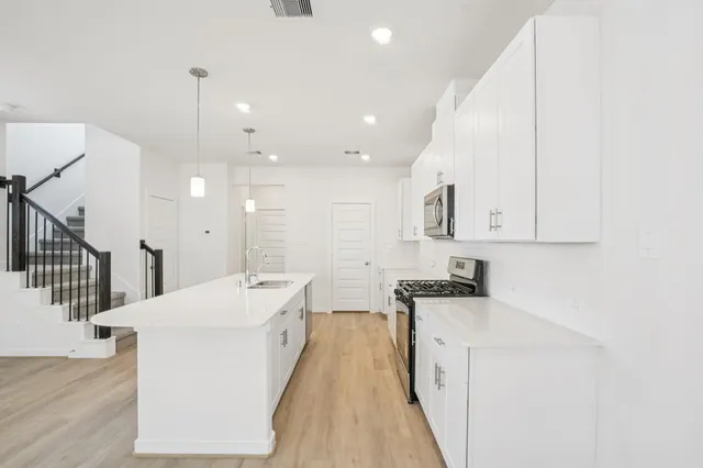 a kitchen with a sink a stove cabinets and wooden floor