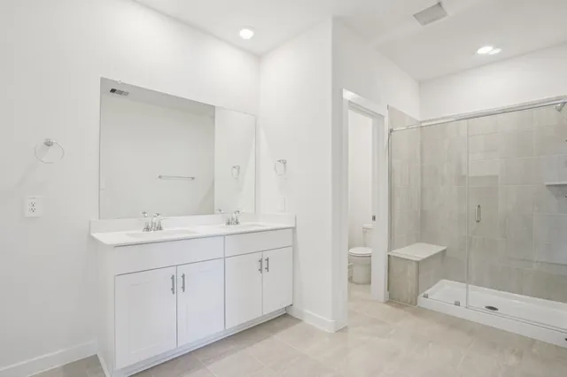 a spacious bathroom with a double vanity sink a toilet and a shower