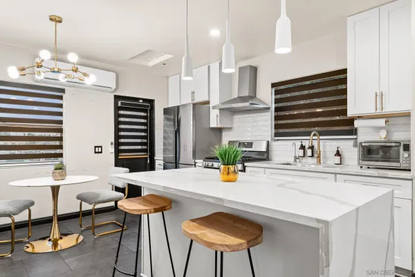 a kitchen with stainless steel appliances a dining table chairs and a refrigerator