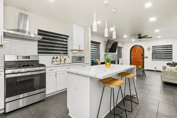 a kitchen with stainless steel appliances a stove a sink a oven a dining table and chairs with wooden floor