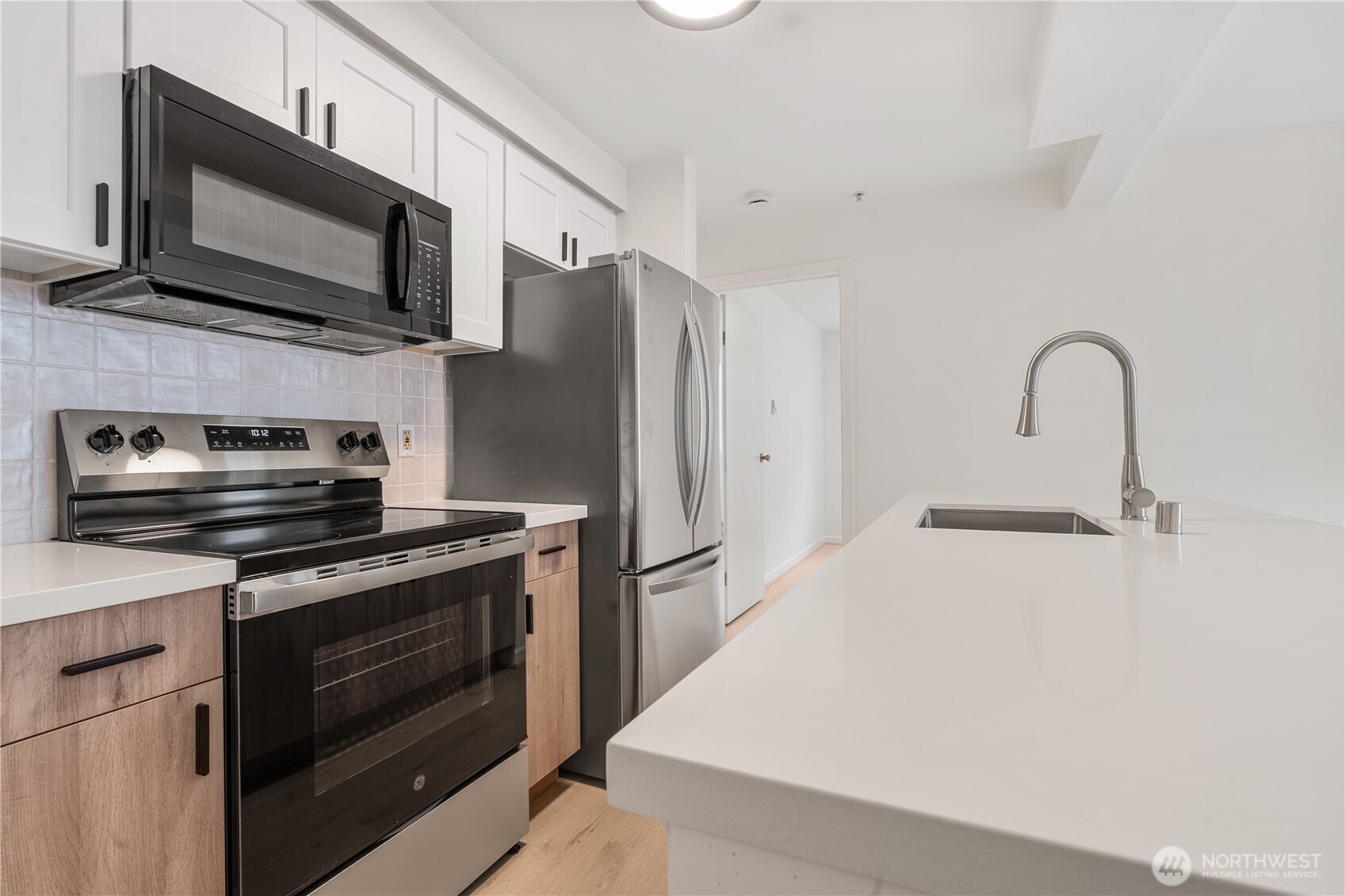 769 Hayes Street, Unit 405 Seattle, WA 98109 - Photo 4 of 29 a kitchen with stainless steel appliances a stove microwave and sink