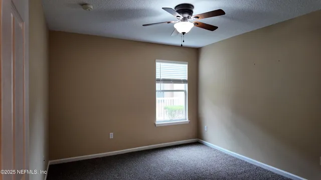 an empty room with a window and a fan
