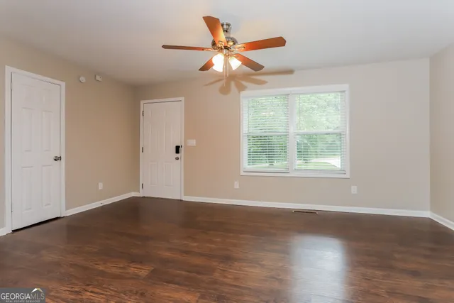 a view of an empty room with wooden floor and a window