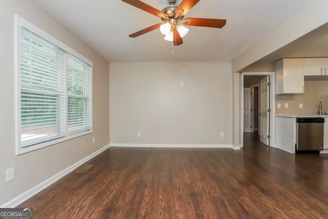 a view of an empty room with window and wooden floor