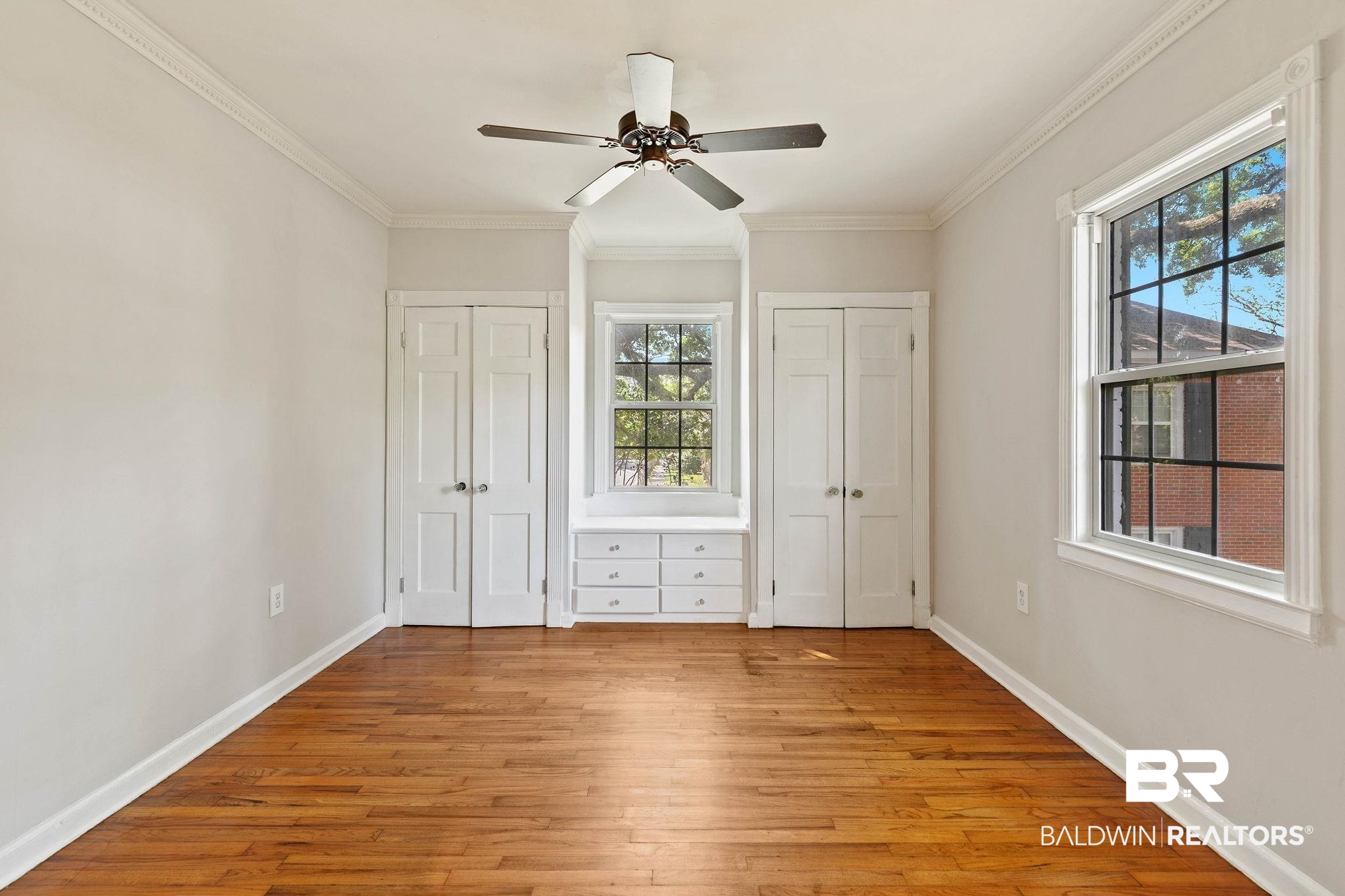 214 Upham Street, Unit 8D Mobile, AL 36607 - Photo 20 of 36 Unfurnished bedroom featuring multiple closets, light wood finished floors, ceiling fan, and crown molding