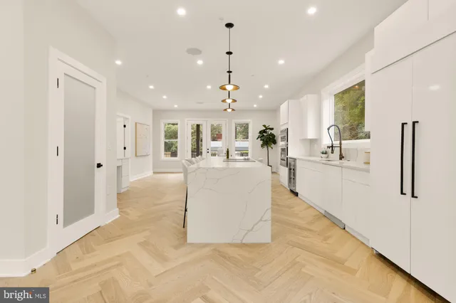 a large white kitchen with a large window a sink and a chandelier