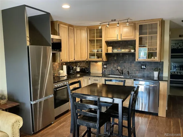 a kitchen with stainless steel appliances granite countertop a refrigerator a sink a stove a table and chairs