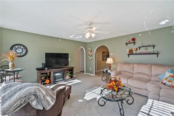 a living room with furniture a flat screen tv and a chandelier