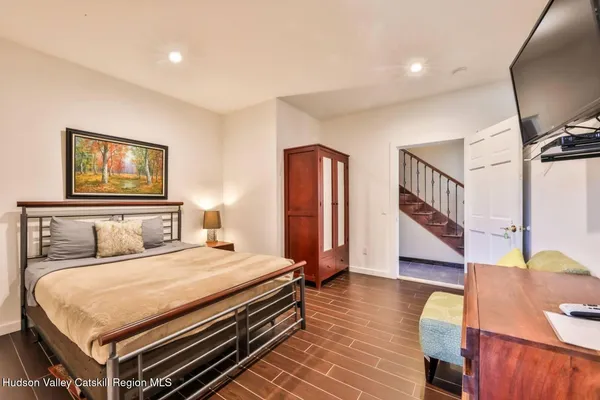 a bedroom with a bed a dresser and wooden floor